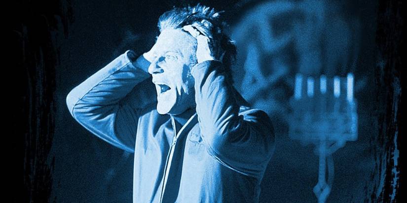 a man holding his head while screaming, bathed in a blue light, in The Legend of Hell House