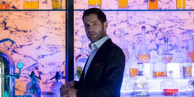 Tom Ellis as Lucifer holding a drink in front of a bar