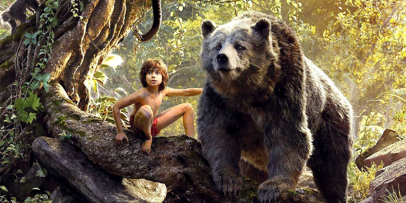 Mowgli and Baloo perch on a tree branch in the Disney live-action version of The Jungle Book.