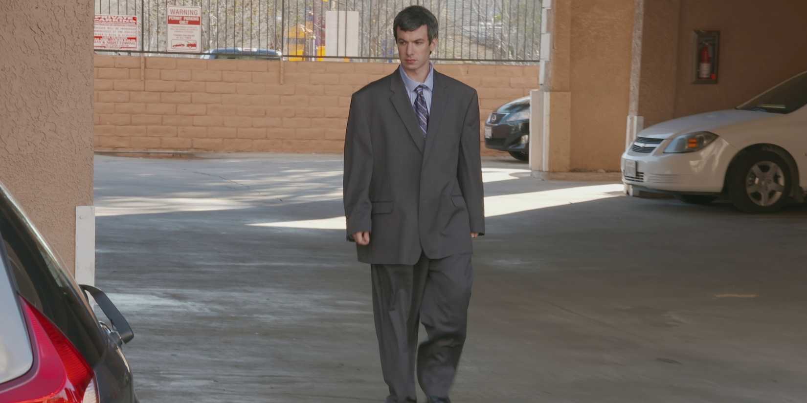 Nathan Fielder wearing suit and walking in a parking lot in Nathan for You