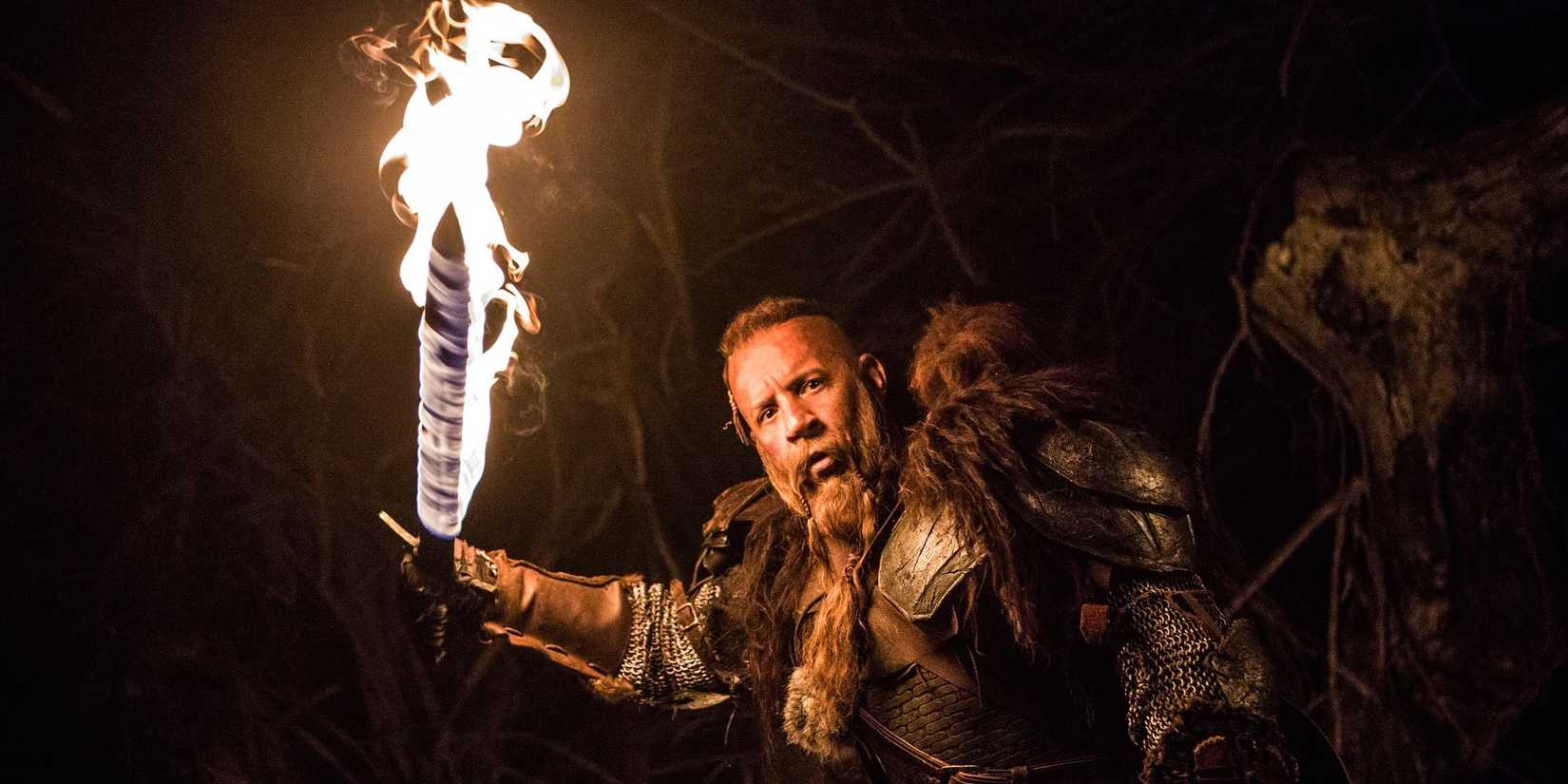 Kaulder holds a flaming sword while exploring a cave in The Last Witch Hunter