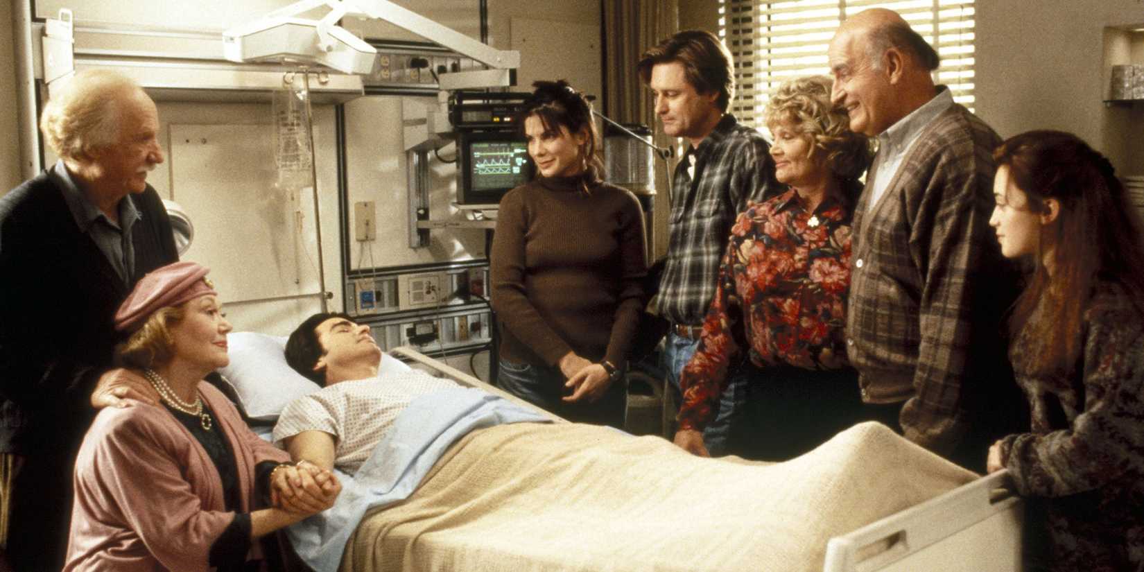 The cast of While You Were Sleeping in the hospital room surrounding the bed.
