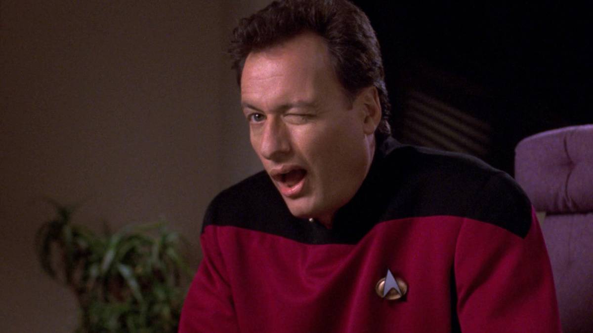 John de Lancie as Q from Star Trek: The Next Generation, standing in a courtroom-like setting with theatrical authority.