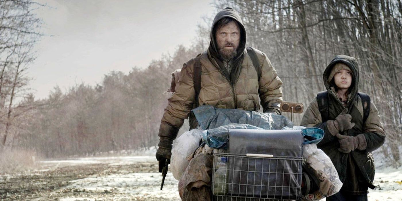 Um homem e uma jovem caminhando por uma estrada vazia em The Road, de 2009