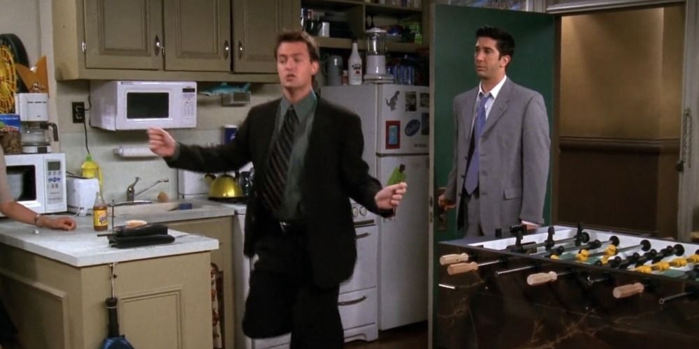 Chandler dances in his apartment unaware that Ross is standing behind him in the doorway in Friends