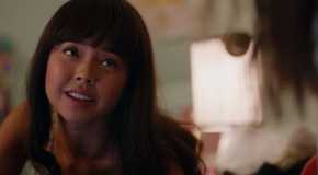 Norah from Ginny & Georgia Lays on a bed and smiles up at one of her friends