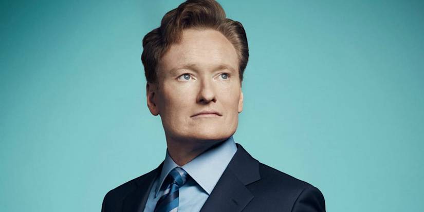 Conan O'Brien posing and looking to the left zoning with a teal background