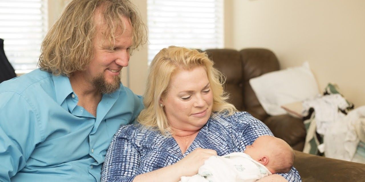 Janelle and Kody Brown holding and looking at a baby on Sister Wives