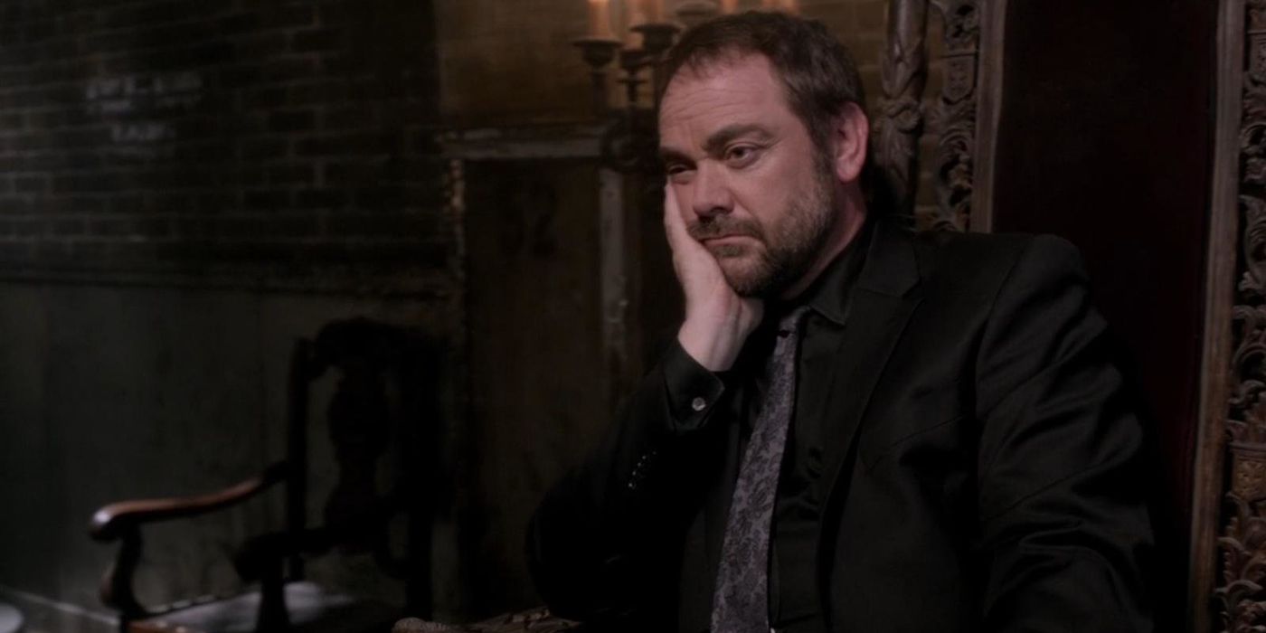 Crowley sitting in a chair in Supernatural