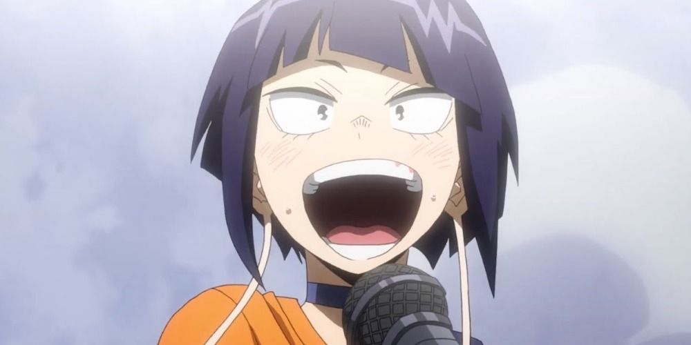 Kyoka Jiro from My Hero Academia singing passionately on stage into a microphone wearing orange shirt