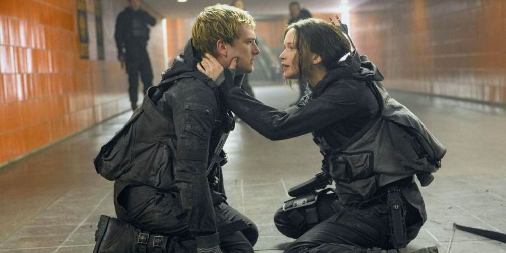 Katniss and Peeta in The Hunger Games dressed in tactical gear, kneeling together on the floor