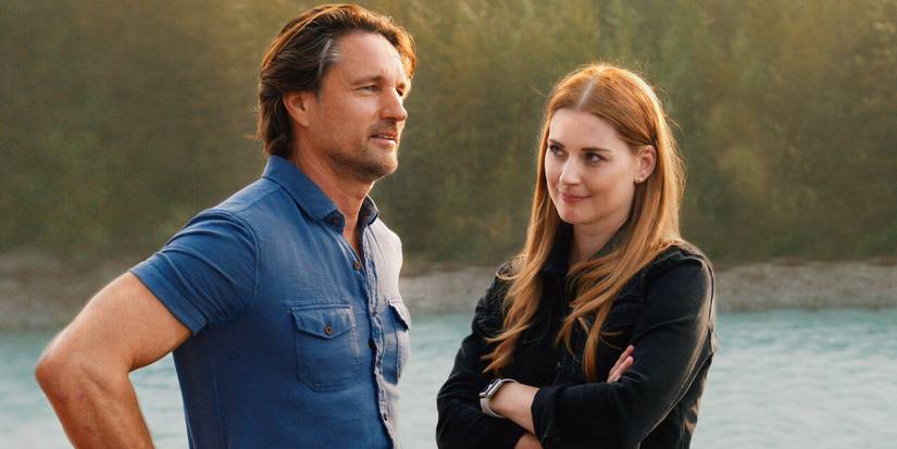 Jack and Mel stand by the river while Mel look at Jack while smiling