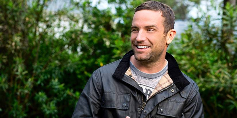 TJ Lavin smiles while posing in front of trees for The Chaellnege promo