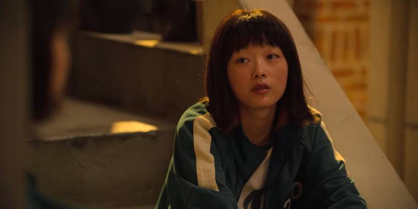 Ji-yeong sitting on the stairs in her blue tracksuit in Squid Game.