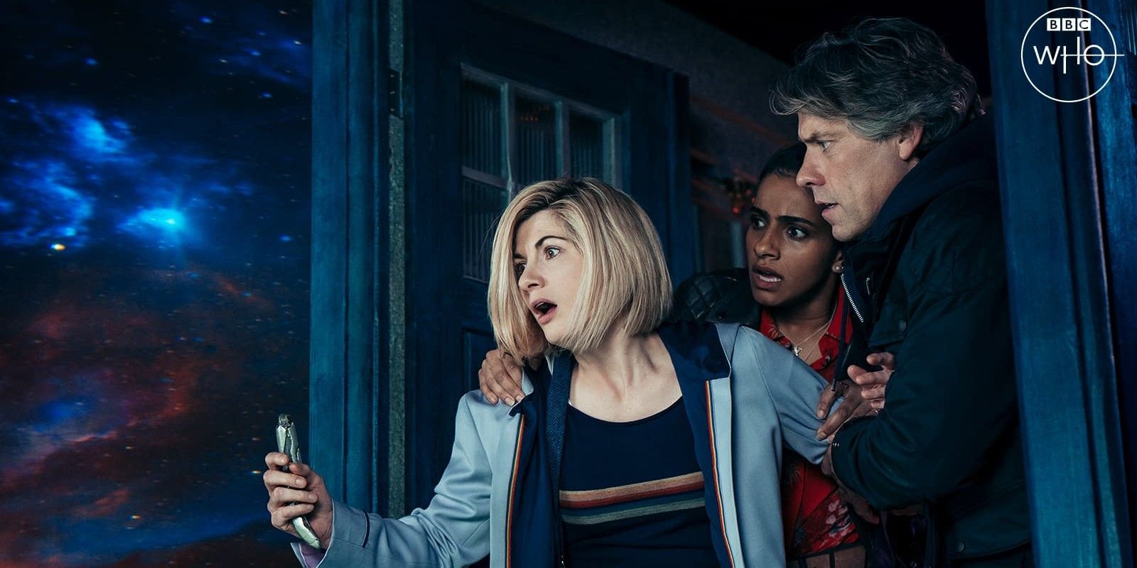 The Doctor looks out at space shocked with her companions behind her.