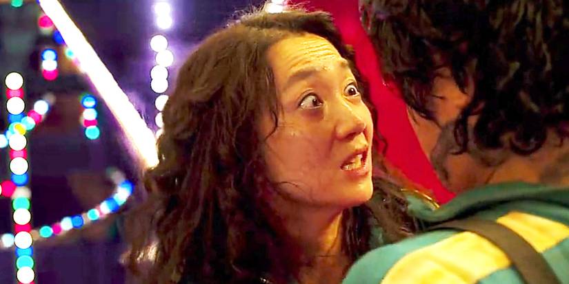 Mi-Nyeo from Squid Game, arms around Jang and wide-eyed.