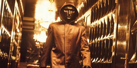The Front Man wearing his mask and jacket as he walks through a hallway in Squid Game.