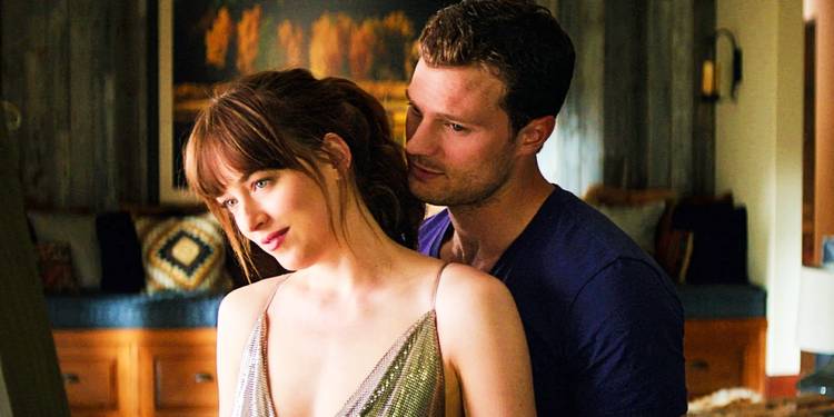 Christian stands behind Ana in 50 Shades of Grey.