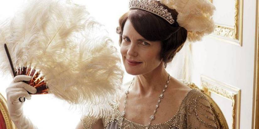 Elizabeth McGovern as Cora Crawley smiling while holding a fan in Downton Abbey