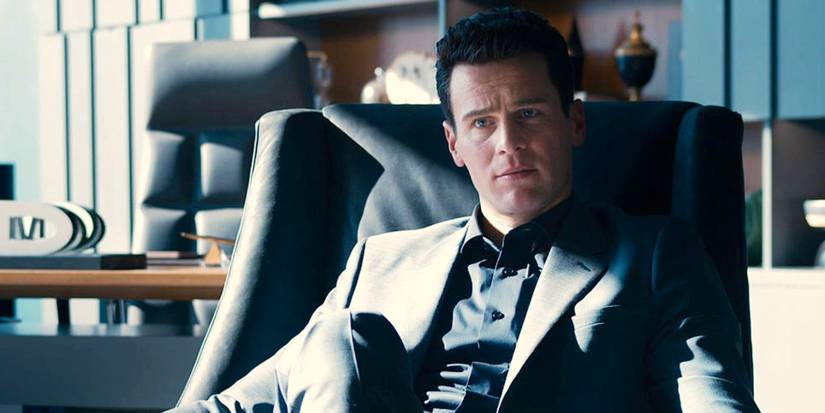 Jonathan Groff as Agent Smith sits in a chair in a modern office in The Matrix Resurrections.