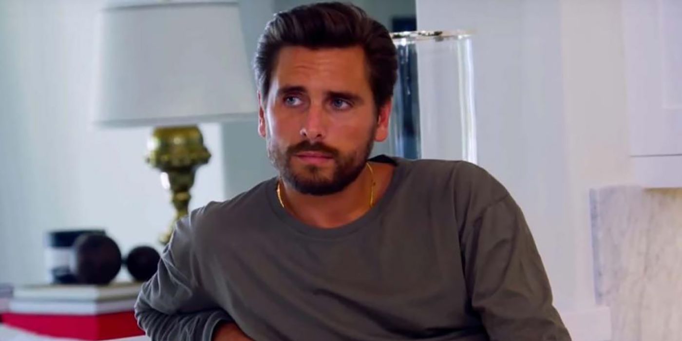 Scott Disick sitting down in a grey sweater, looking to the left.