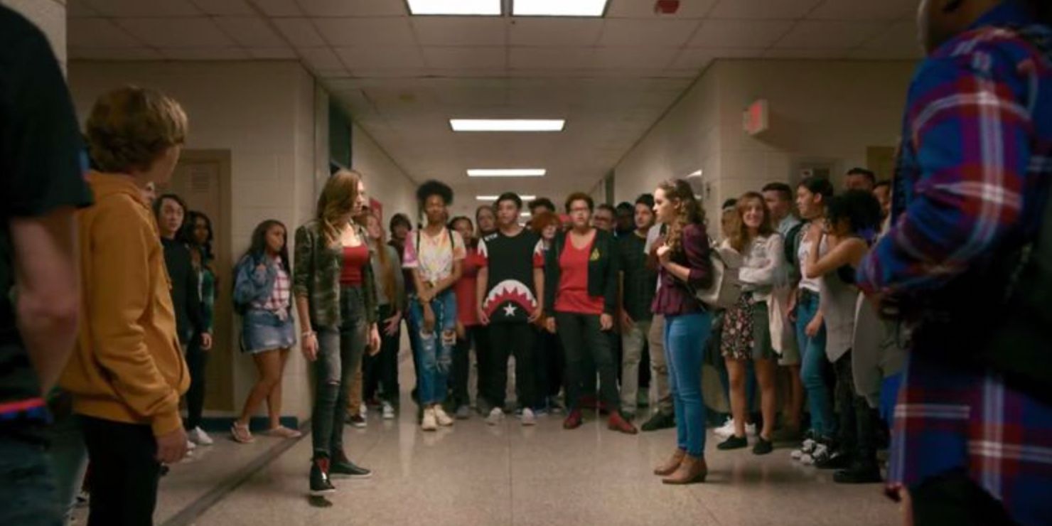 Tory and Sam face off in a crowd of students in the high school in Cobra Kai