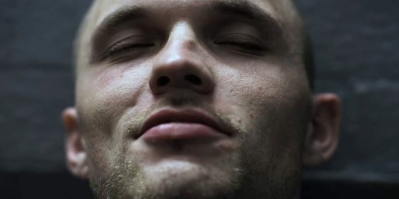 Ed Skrein smiling with his eyes closed in a prison cell in Ill Manors