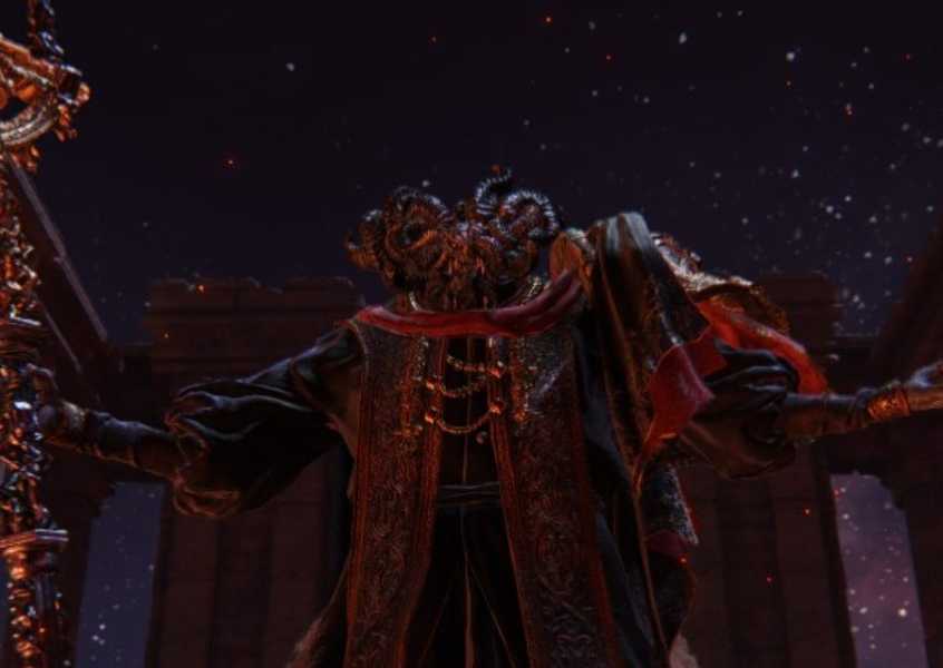 Mohg, Lord of Blood in Elden Ring. He holds his staff in his right hand while also lifting his left hand. His face is filled with horns which make it near undescribably. He stands in a dark arena with the underground portion of the map's night sky filled with glistening stars.