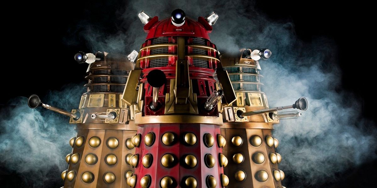 2 bronze Daleks and the Supreme Dalek infront of a black background surrounded by smoke