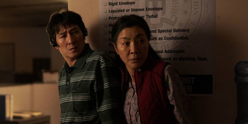 Веймон (Ке Хуи Куан) и Эвелин (Мишель Йео) смотрят в сторону в темной комнате в фильме Everything Everywhere All at Once.