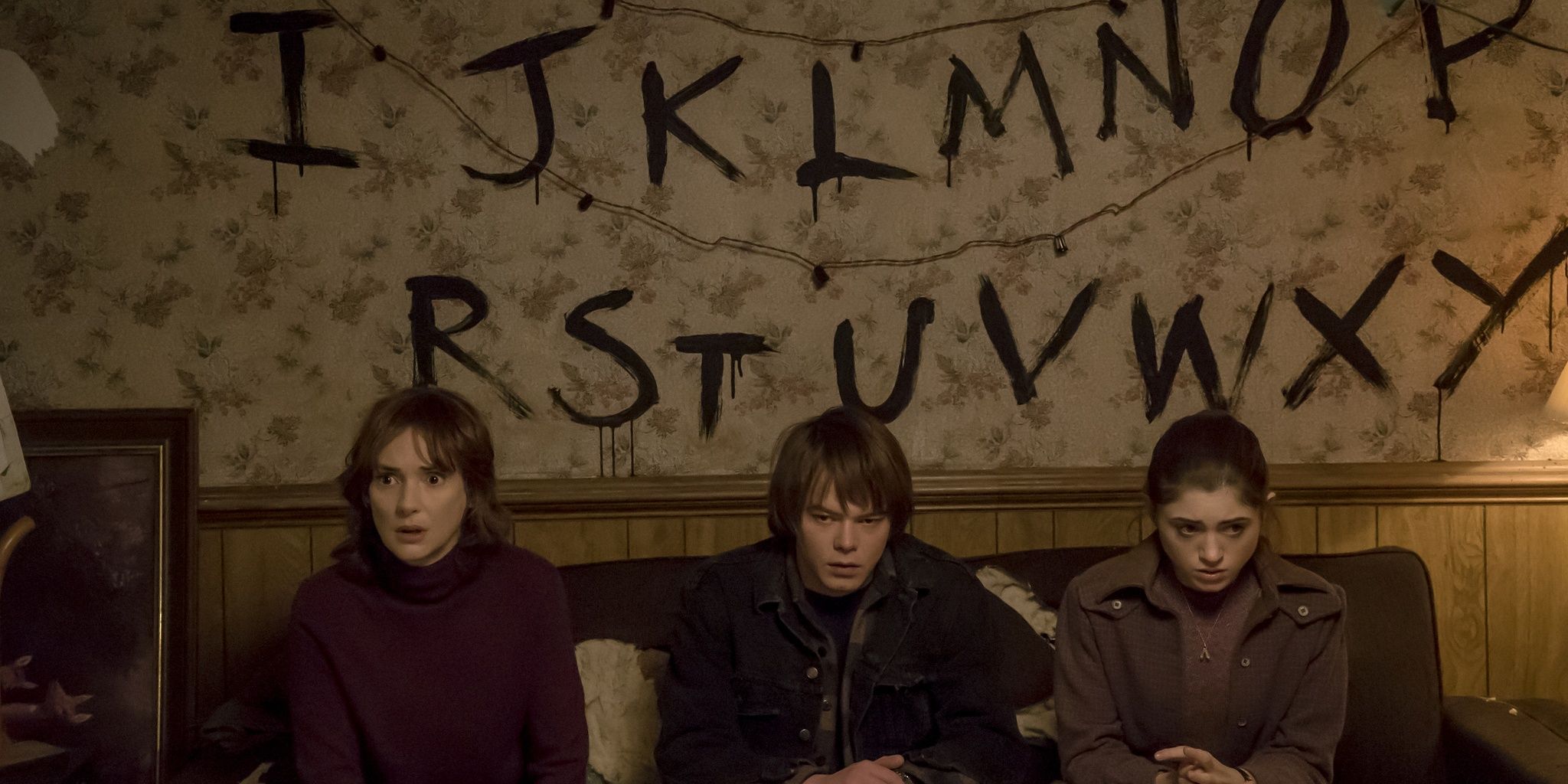 Joyce Nancy and Jonathan sitting by a decaying wall in Stranger Things Cropped