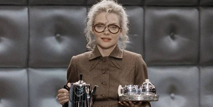 Michelle Pfeiffer como Selina Kyle em Batman: O Retorno segurando um bule e xícaras