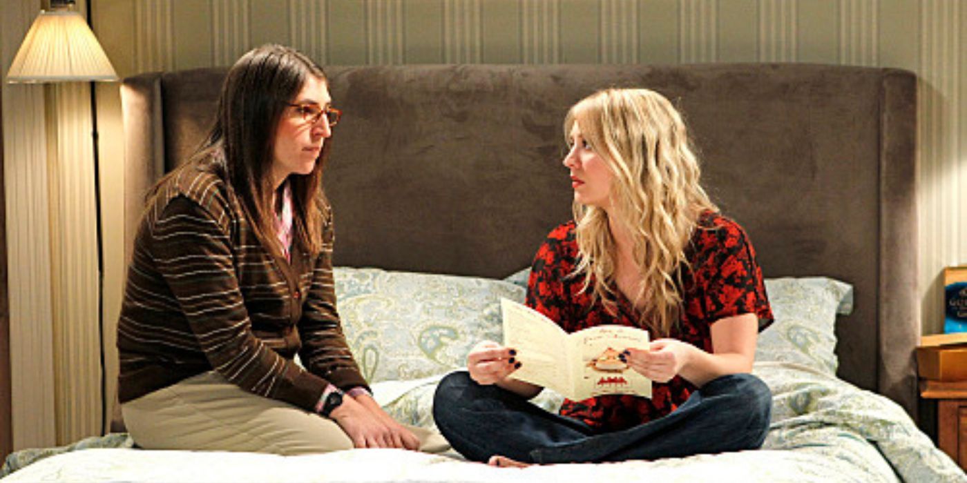 Penny and Amy sitting on a hotel bed on TBBT
