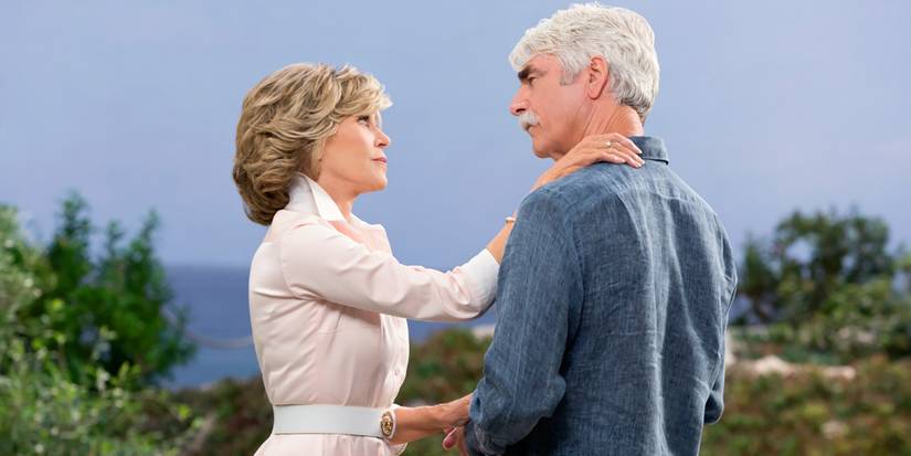 Grace and Phil from Grace and Frankie with their hands on one another.