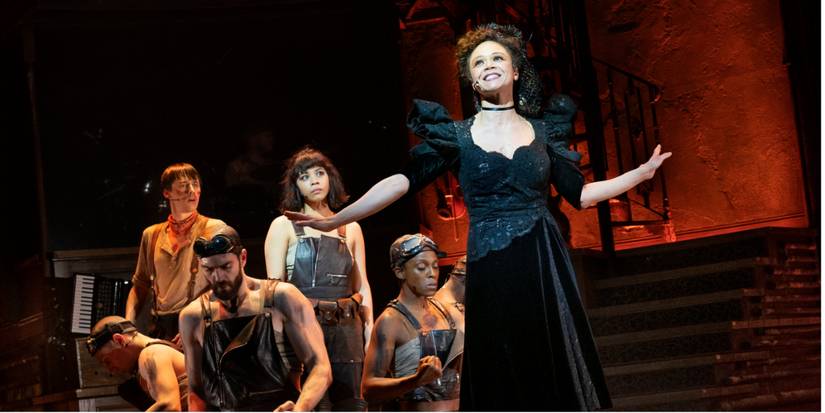 Perséfone de Hadestown canta em frente a Orfeu e Eurídice.