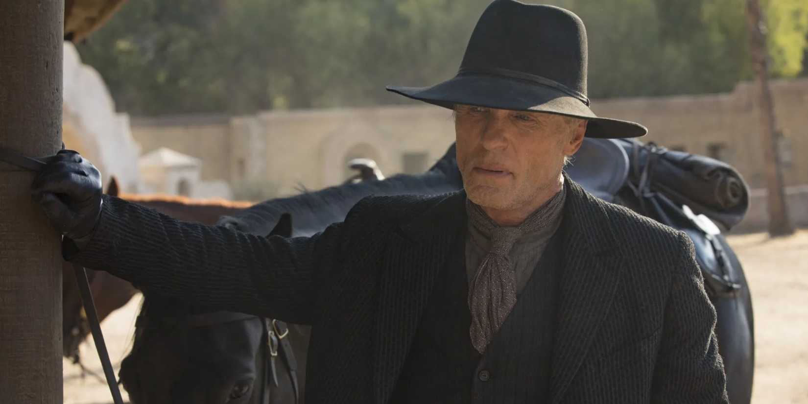 Der Mann in Schwarz (Ed Harris) sieht ernst aus und steht neben Pferd und Kutsche in Westworld