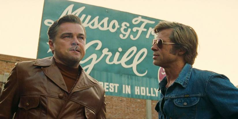 Once Upon a Time in Hollywood Leonardo DiCaprio as Rick Dalton and Brad Pitt as Cliff Booth talking in front of a sign