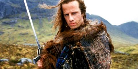 Christopher Lambert as Connor MacLeod holding a sword on a mountain in Highlander.