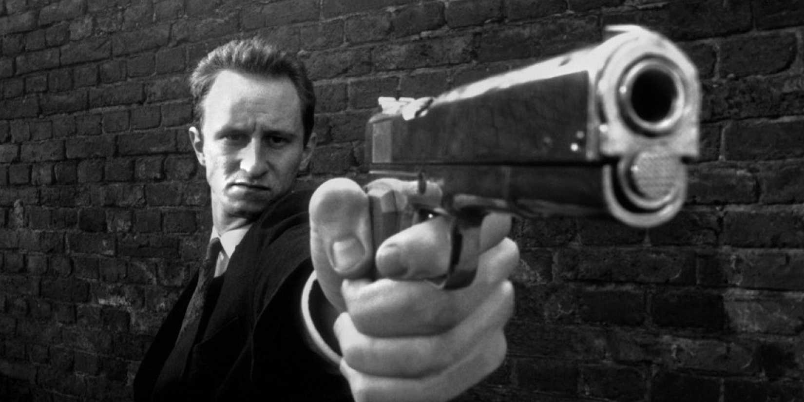 A man points a gun close to the camera in Man Bites Dog 