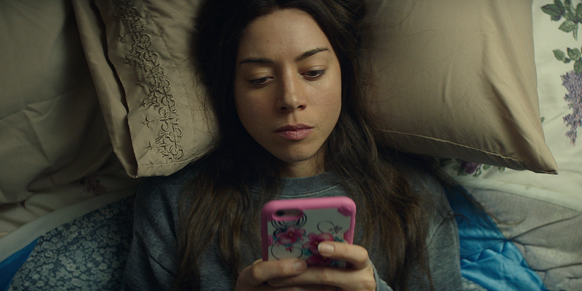 A girl lies on her bed and is on her phone in Ingrid Goes West.