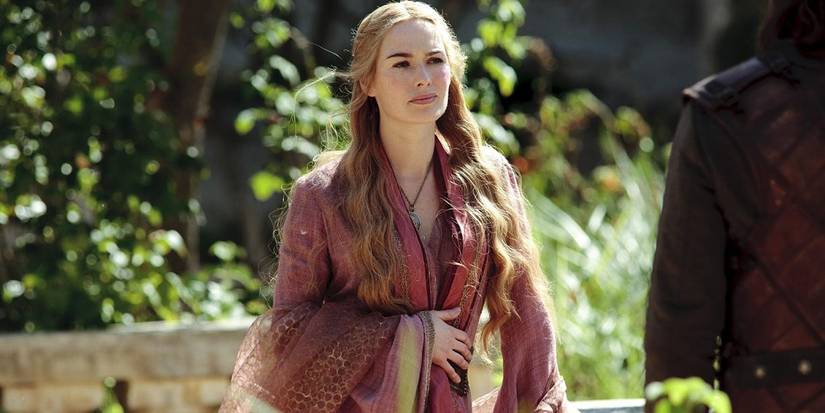 13 Female Characters Who Redefined Strength On TV 5 Cersei Lannister wearing a red and yellow dress in a garden talking to someone in Game of Thrones season 1