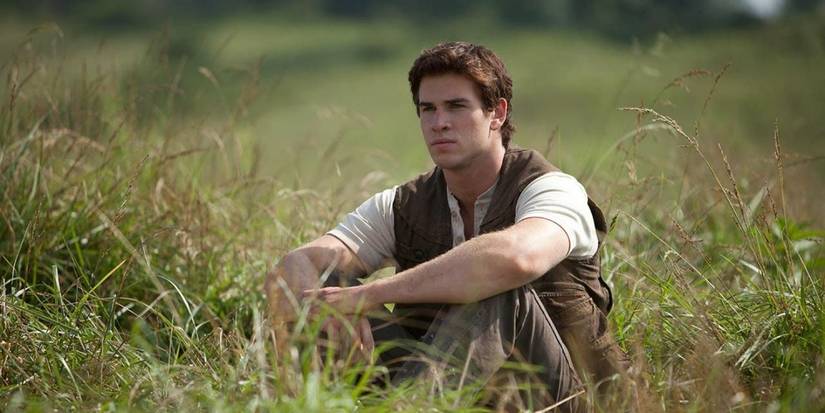 Gale (Liam Hemsworth) sentado apenas no prado nos Jogos Vorazes. 