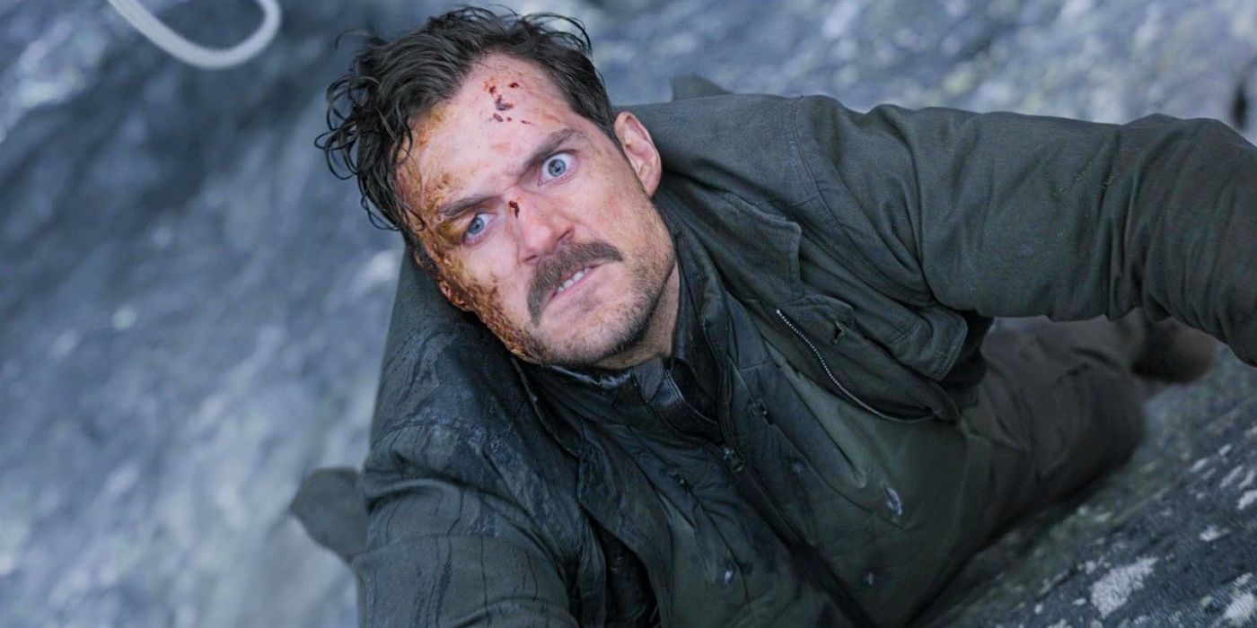 August Walker (Henry Cavill) hanging from a cliff and looking up with a scared expression in Mission: Impossible - Fallout.