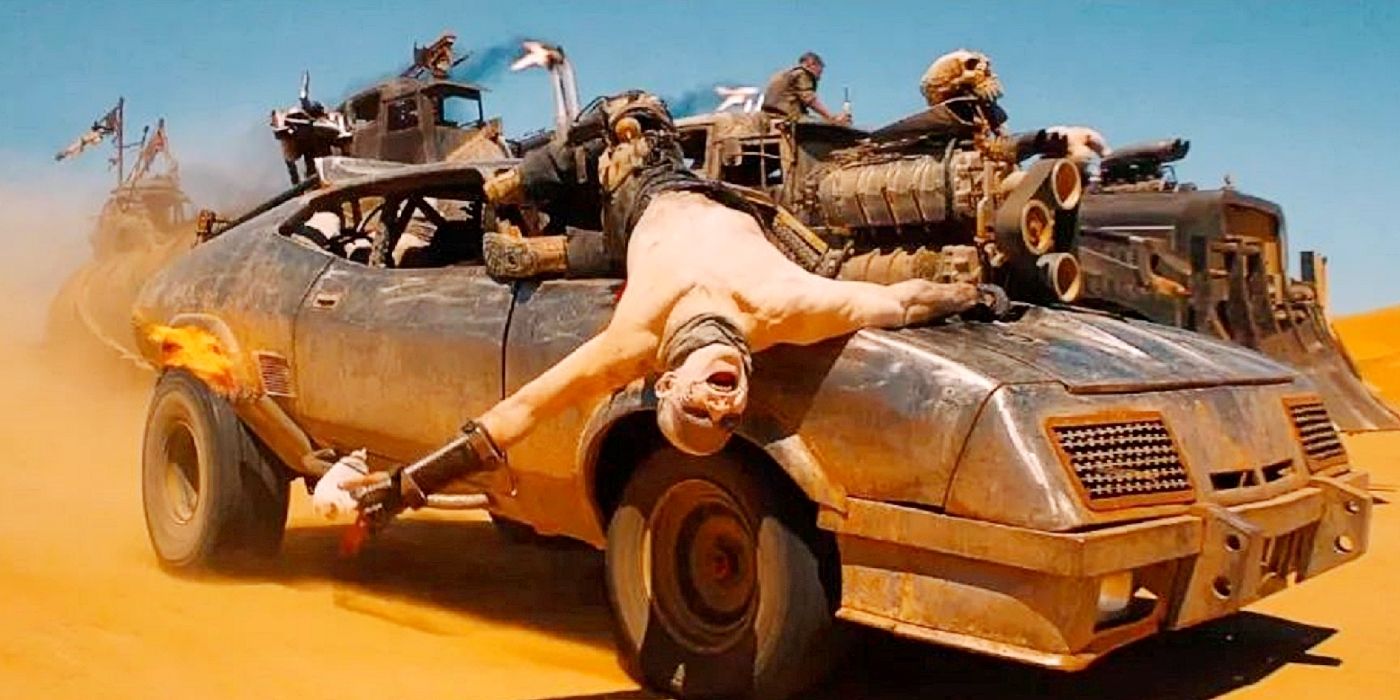 Um War Boy pendurado em um muscle car em movimento em Mad Max: Fury Road.