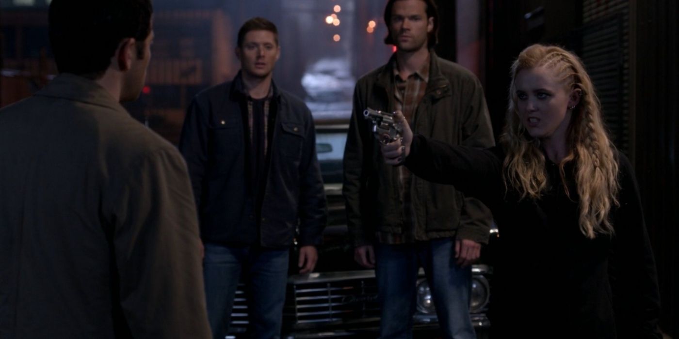 Claire holding Castiel at gunpoint with Sam and Dean behind her in Supernatural