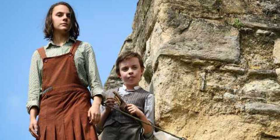 An image of Lyra and Roger standing on a cliff in His Dark Materials