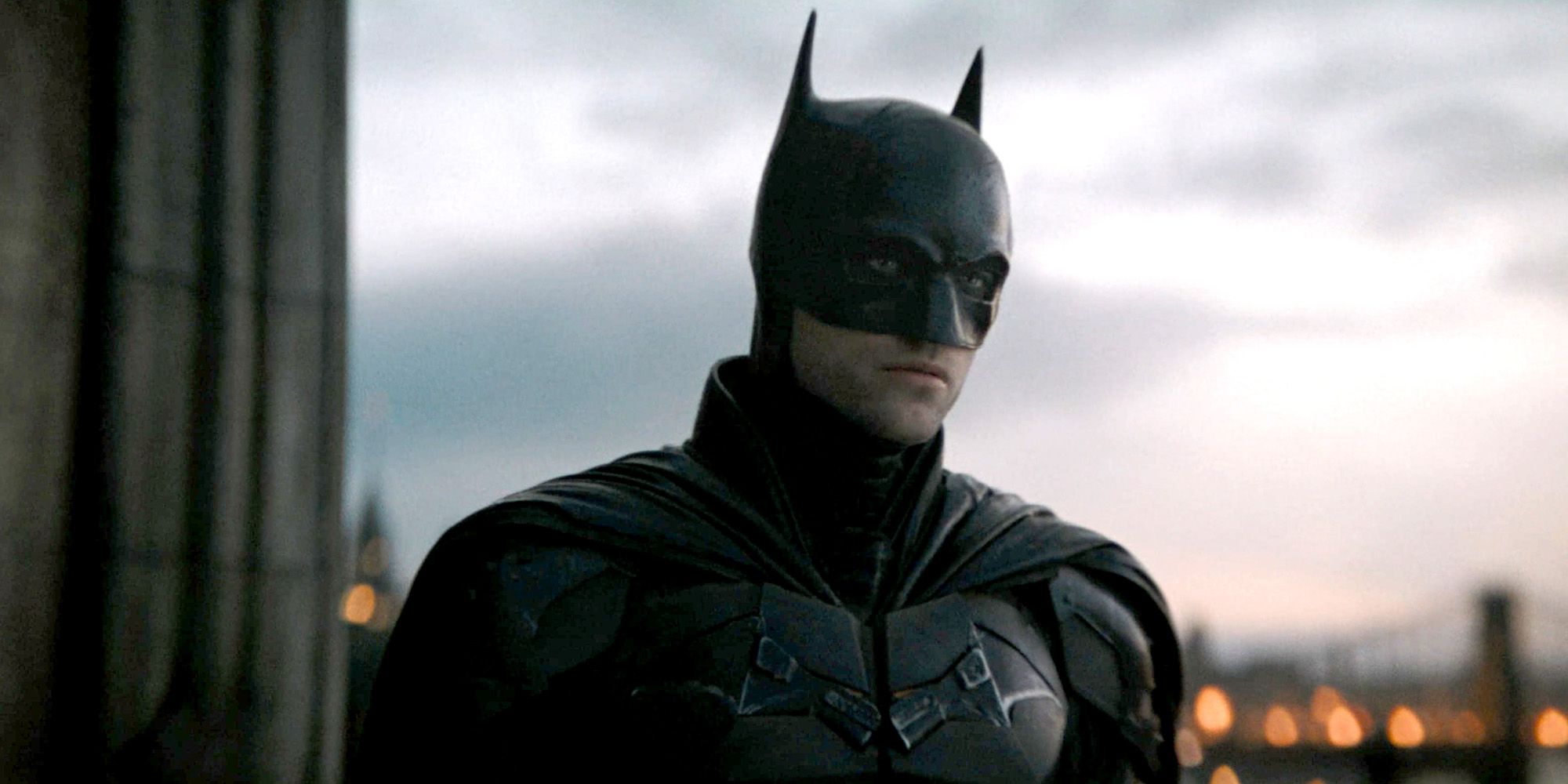 Robert Pattinson as Batman standing on a rooftop