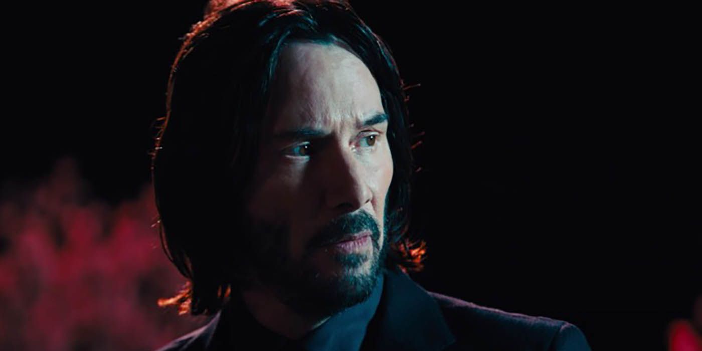 John Wick looking put together, standing in a dark room.