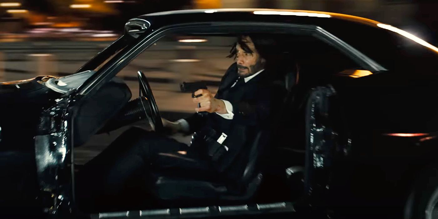 Keanu Reeves menembakkan pistol saat mengendarai mobil di John Wick: Bab 4.