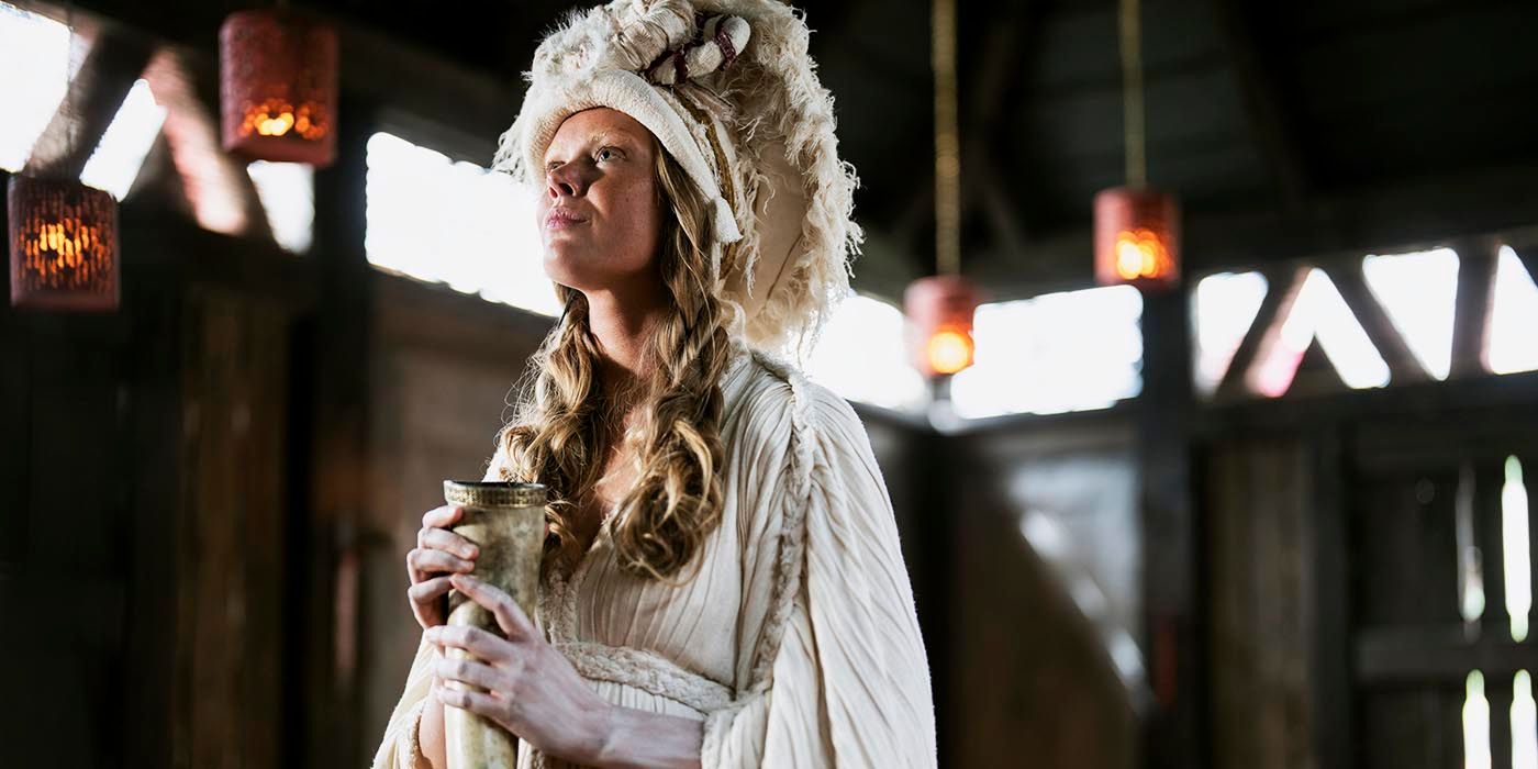 Freydis holds a horn goblet and looks up while wearing a headdress in Vikings: Valhalla